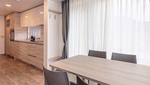 A modern kitchen with wooden cabinets, a built-in oven, and a coffee machine. There is a dining area with a wooden table and chairs. - Chalet in Kotschach Near Ski Area Vorhegg (Kotschach-Mauthen)