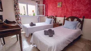 Una habitación con dos camas, un escritorio y una ventana con cortinas.