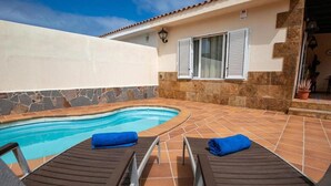 Ein Swimmingpool mit zwei Liegestühlen und einer Steinmauer.