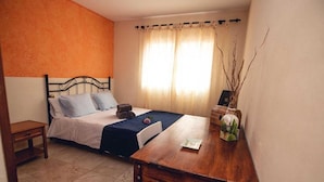 Ein Schlafzimmer mit einem Bett, einem Nachttisch und einem kleinen Holztisch mit einer Vase.