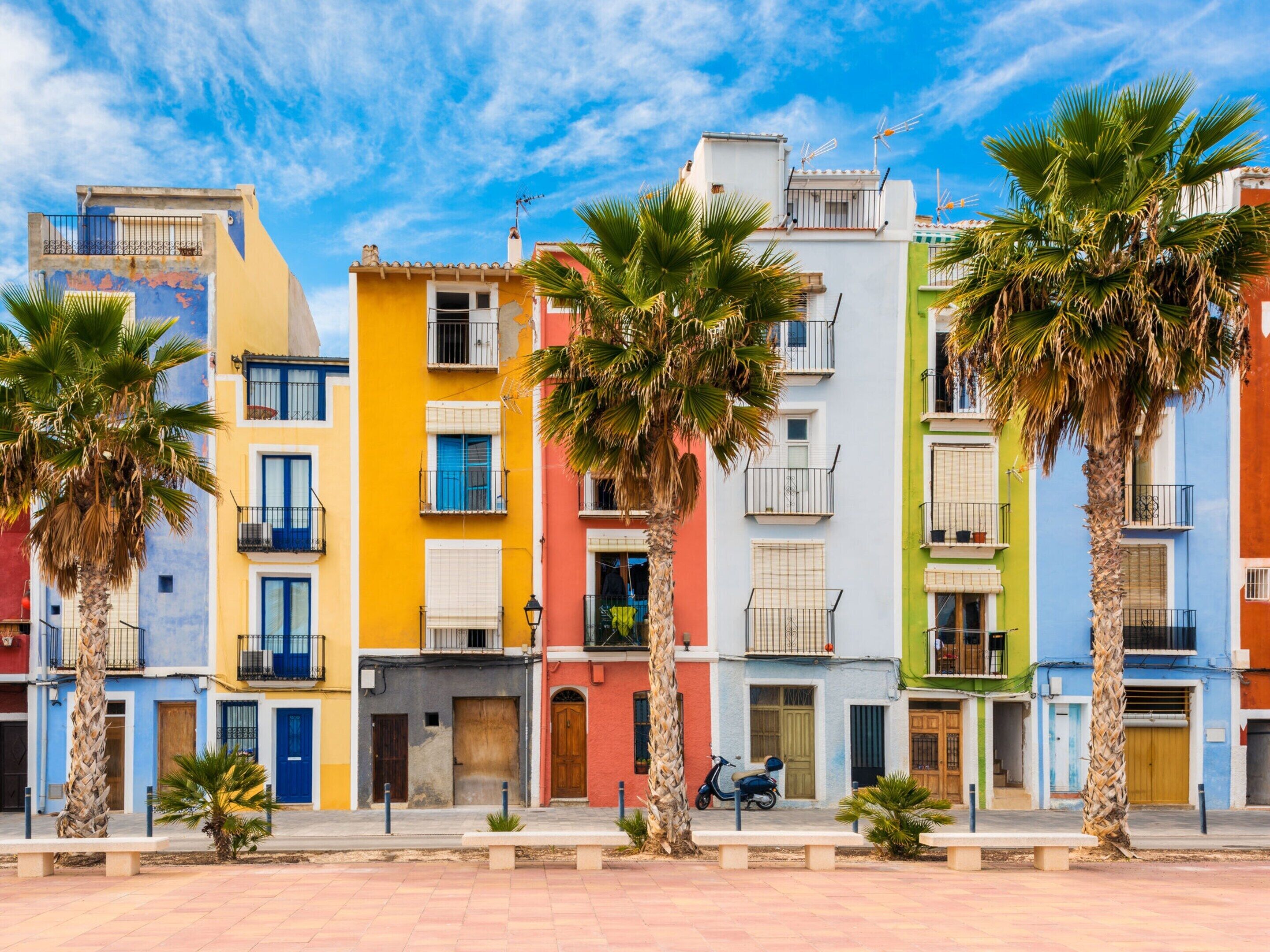 Une rangée de bâtiments colorés, dotés de balcons et bordés de palmiers.