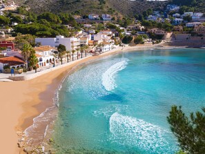 Un pueblo costero con aguas turquesas cristalinas, playas de arena y edificios blancos con tejados rojos.