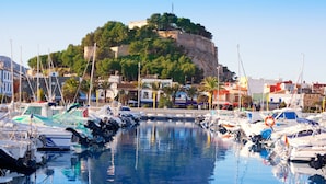 A marina with boats docked, a clear sky, and a historic building on a hill in the background. - Nice Mediterranean Furnished Apartment in Altea (Altea)