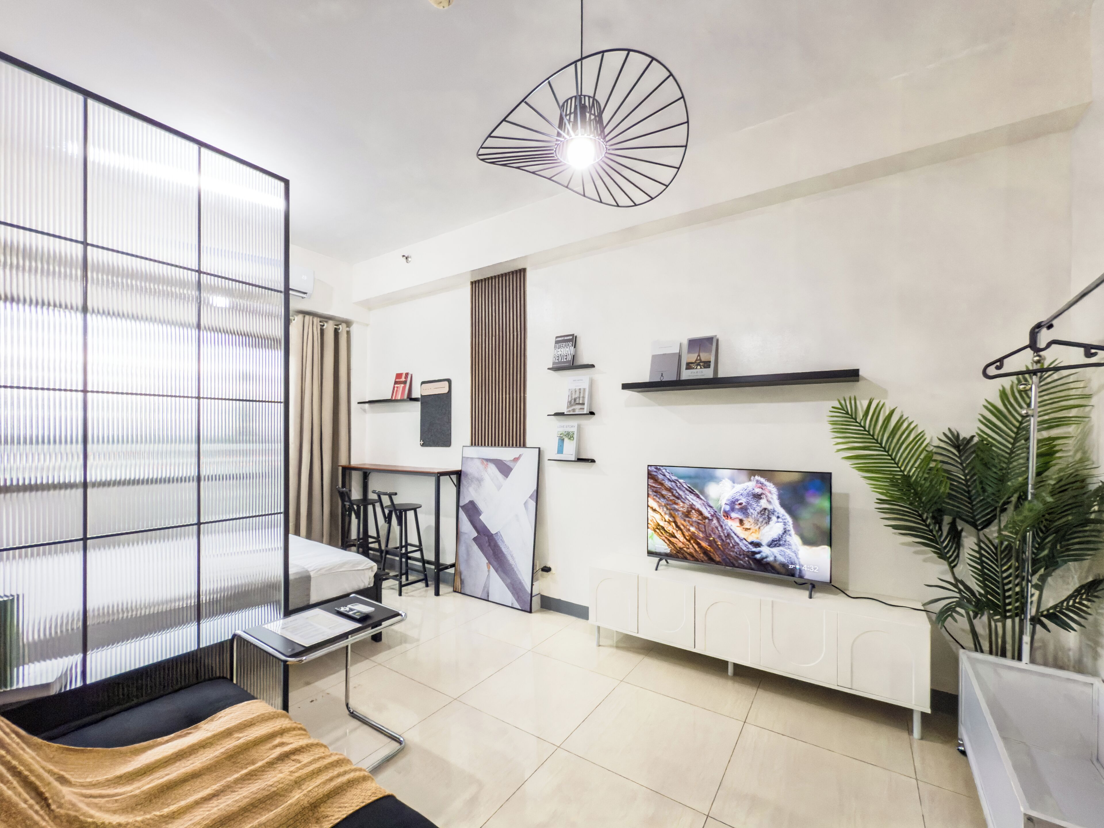 A modern living room with a sofa, a TV, a coffee table, and a plant.