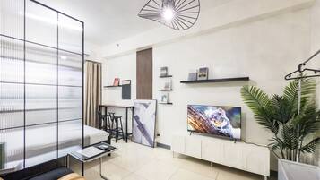 A modern living room with a sofa, a TV, a coffee table, and a plant.