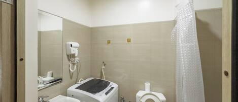 Un baño pequeño con lavamanos, secador de pelo, inodoro y cortina de ducha.