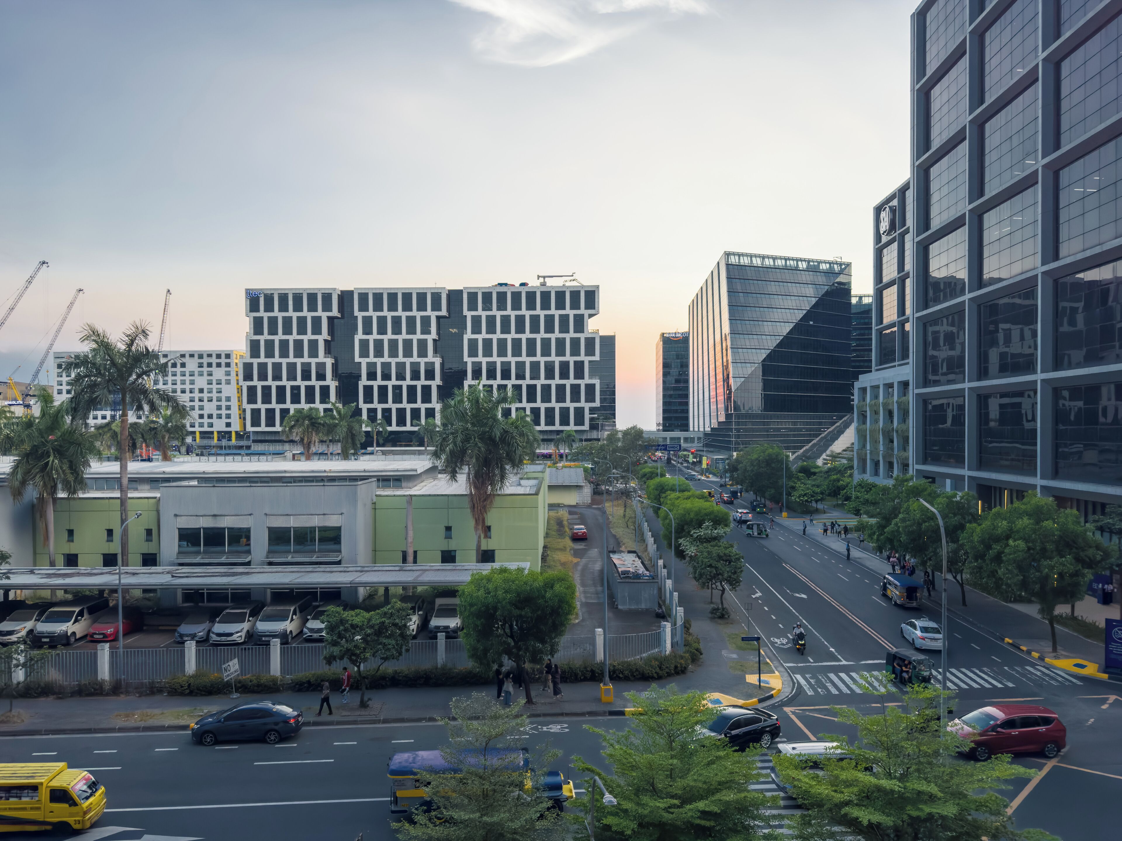 A modern urban street with high-rise buildings, a pedestrian crossing, and a mix of vehicles and pedestrians.