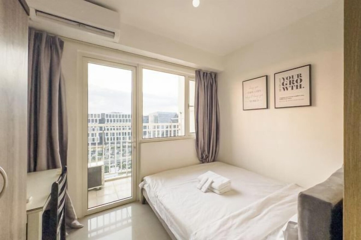 A hotel room with a bed, a view through a sliding door, and two framed motivational quotes on the wall.