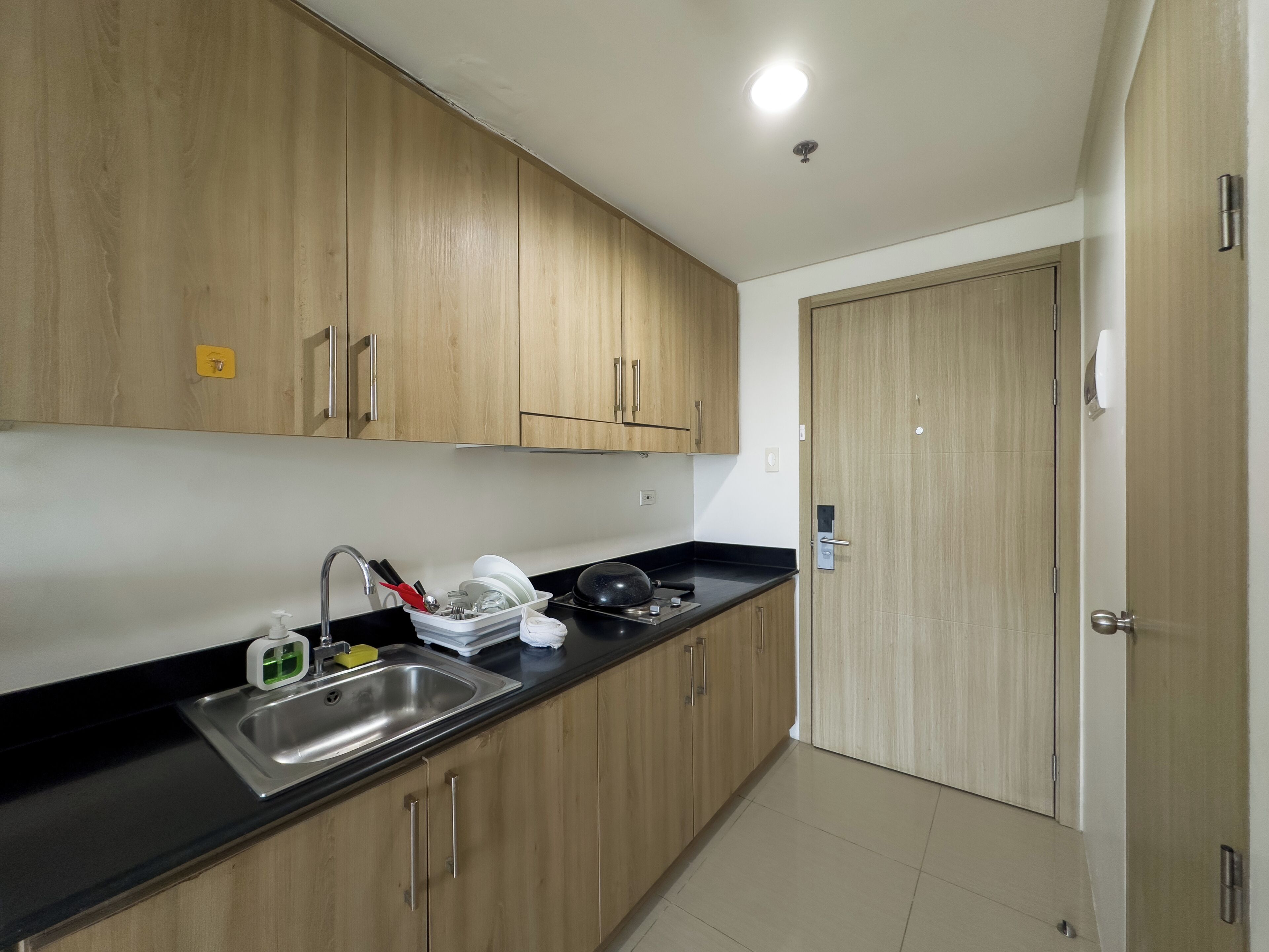 A kitchen with wooden cabinets, a black countertop, and a stainless steel sink.