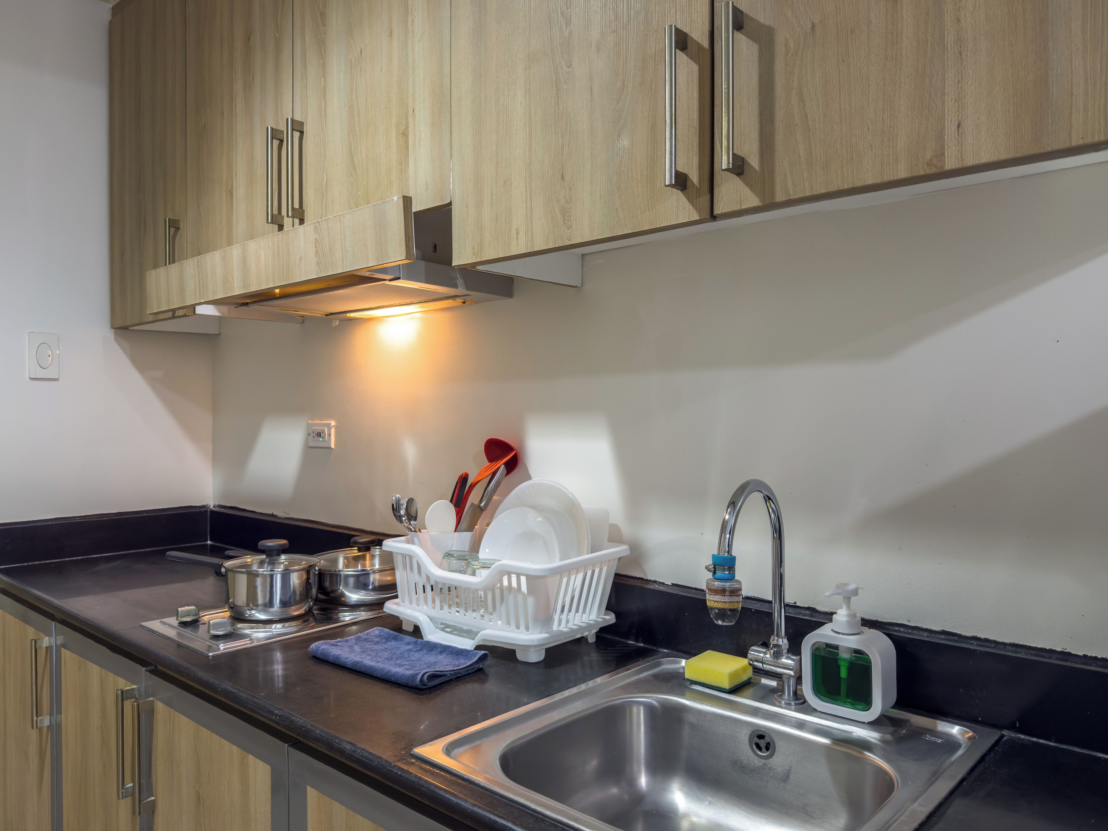 A modern kitchen with stainless steel appliances, wooden cabinets, and a black countertop.