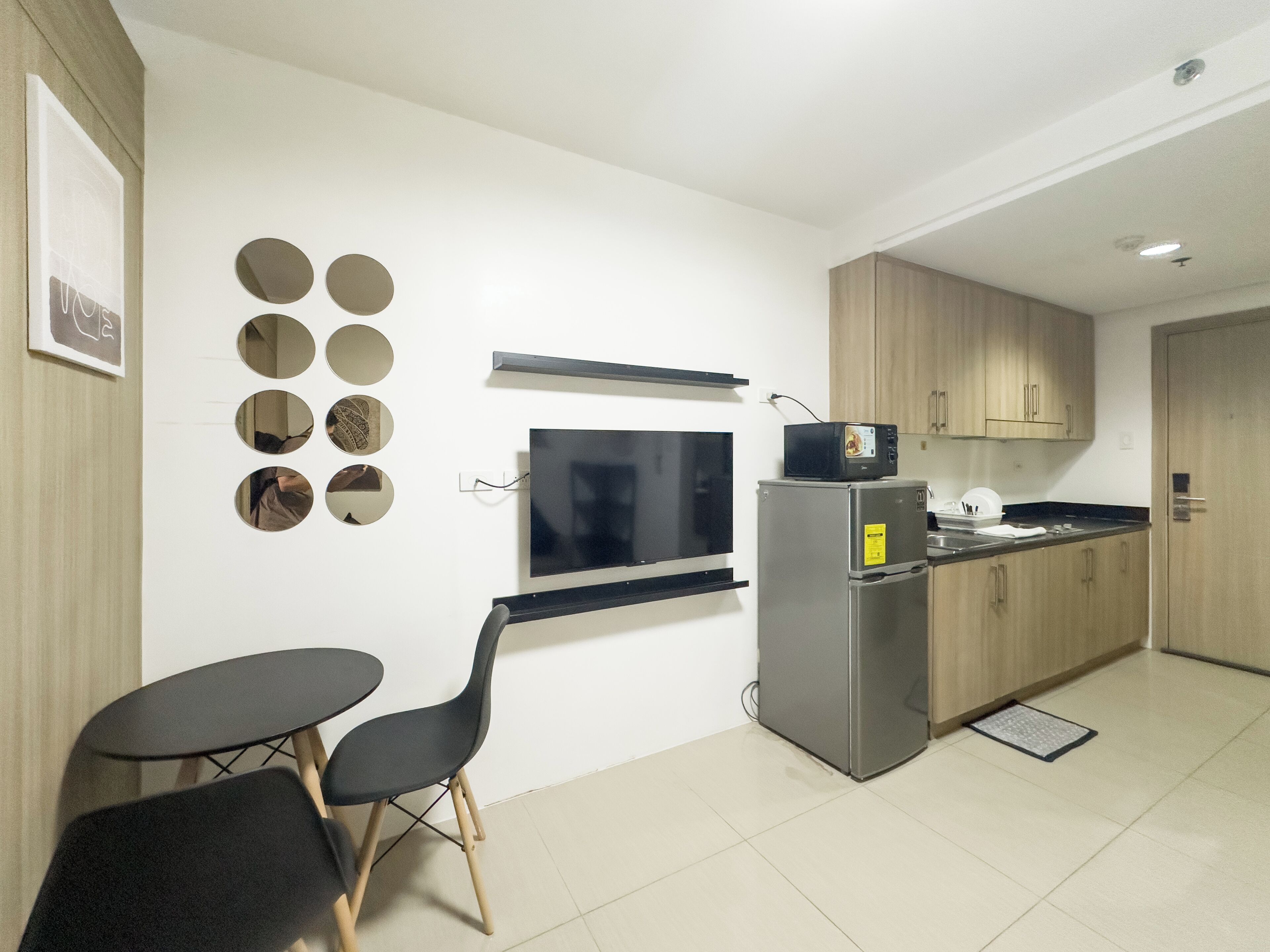 A compact kitchen with a refrigerator, microwave, and a small dining table with chairs.