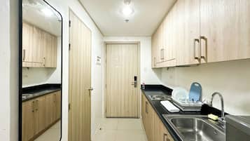A narrow kitchen with wooden cabinets, a stainless steel sink, and a black countertop.