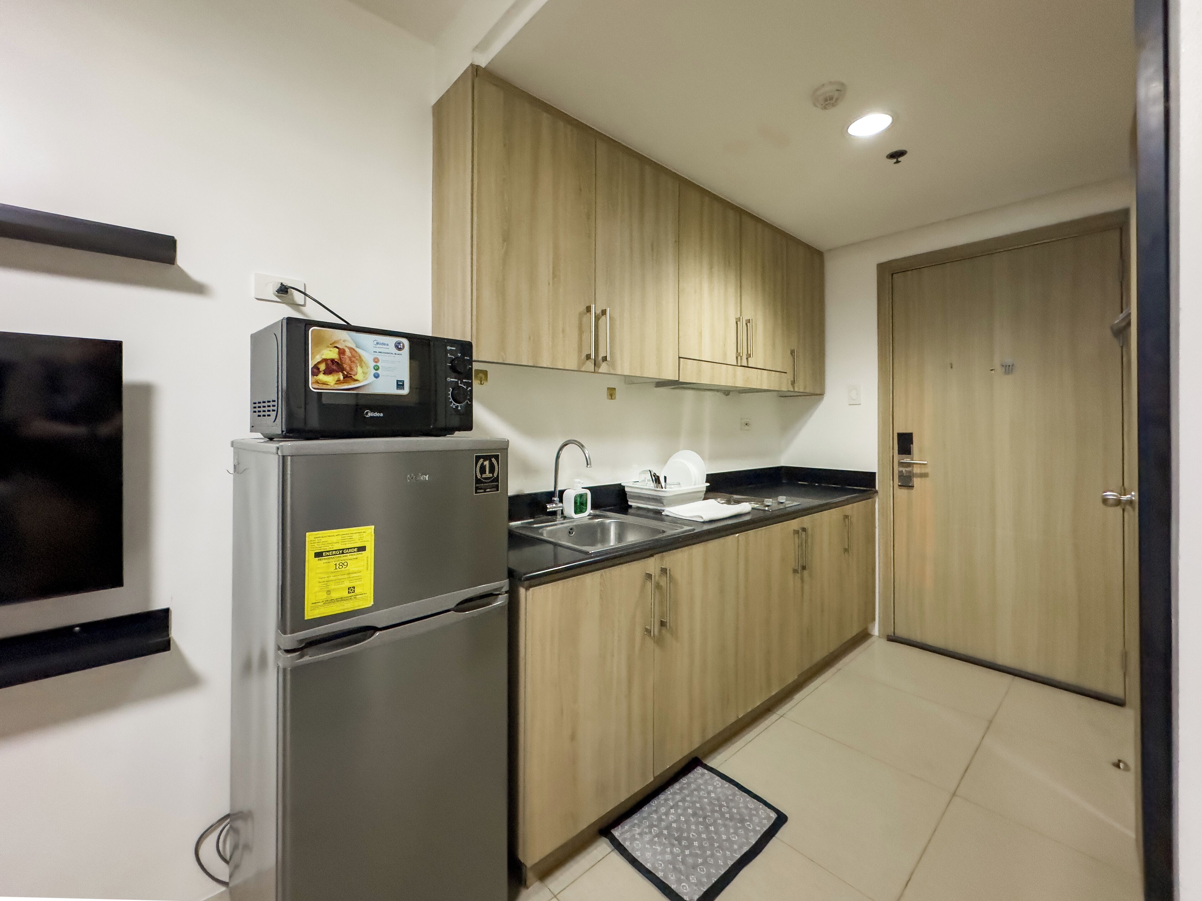 A compact kitchen with a refrigerator, microwave, sink, and wooden cabinets.
