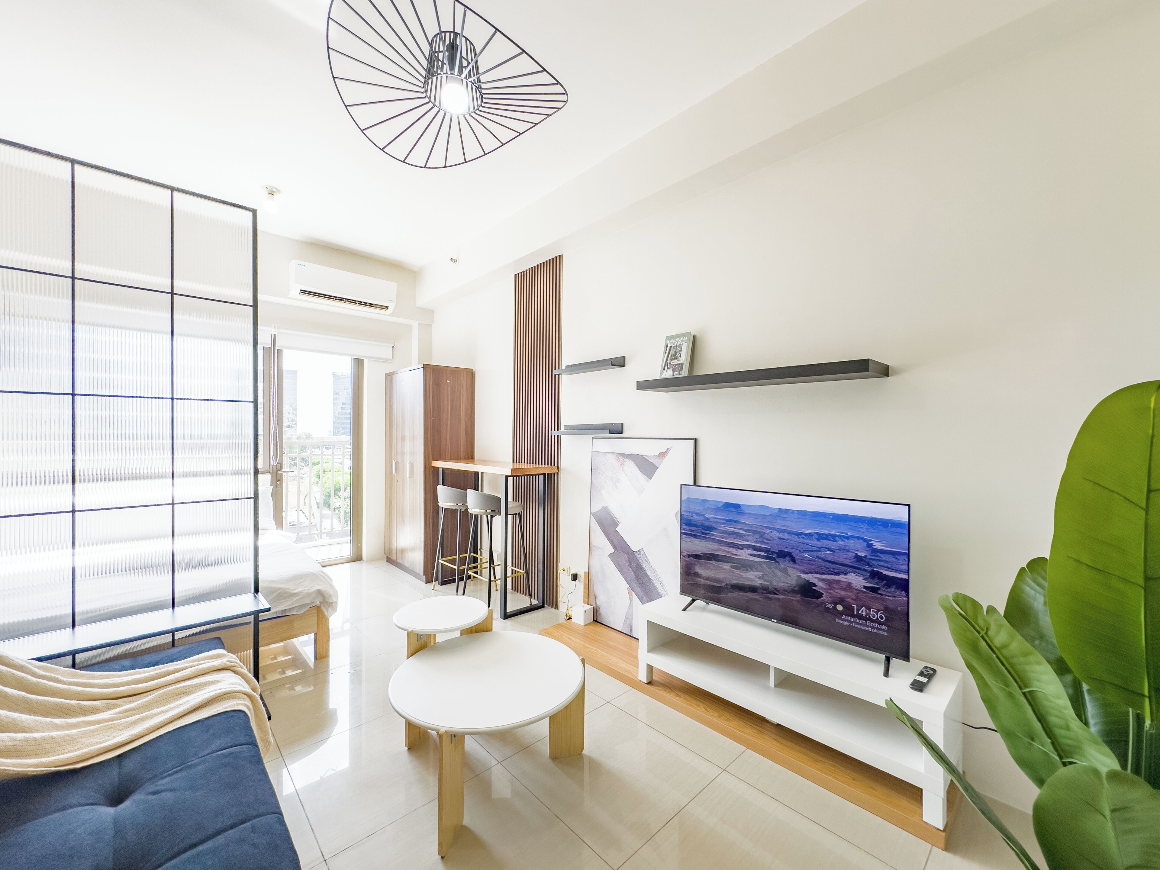 A modern living room with a large flat-screen TV, a sofa, a coffee table, and a dining area.