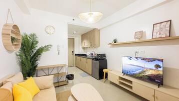 Una sala moderna con un sofá, una mesa de centro, un televisor y una cocina al fondo.