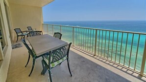 Ein Balkon mit Tisch und Stühlen, der einen ungehinderten Blick auf das Meer bietet.
