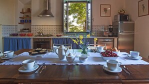 A kitchen with a dining table set for breakfast, a stove, and a window with a view of trees. - Tuscan Holiday Home With Pool (Chiusi)