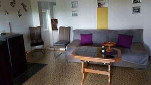 A living room with a sofa, chairs, a coffee table, and a television. - Haus Elfi Modern Retreat (Lutherstadt Eisleben)