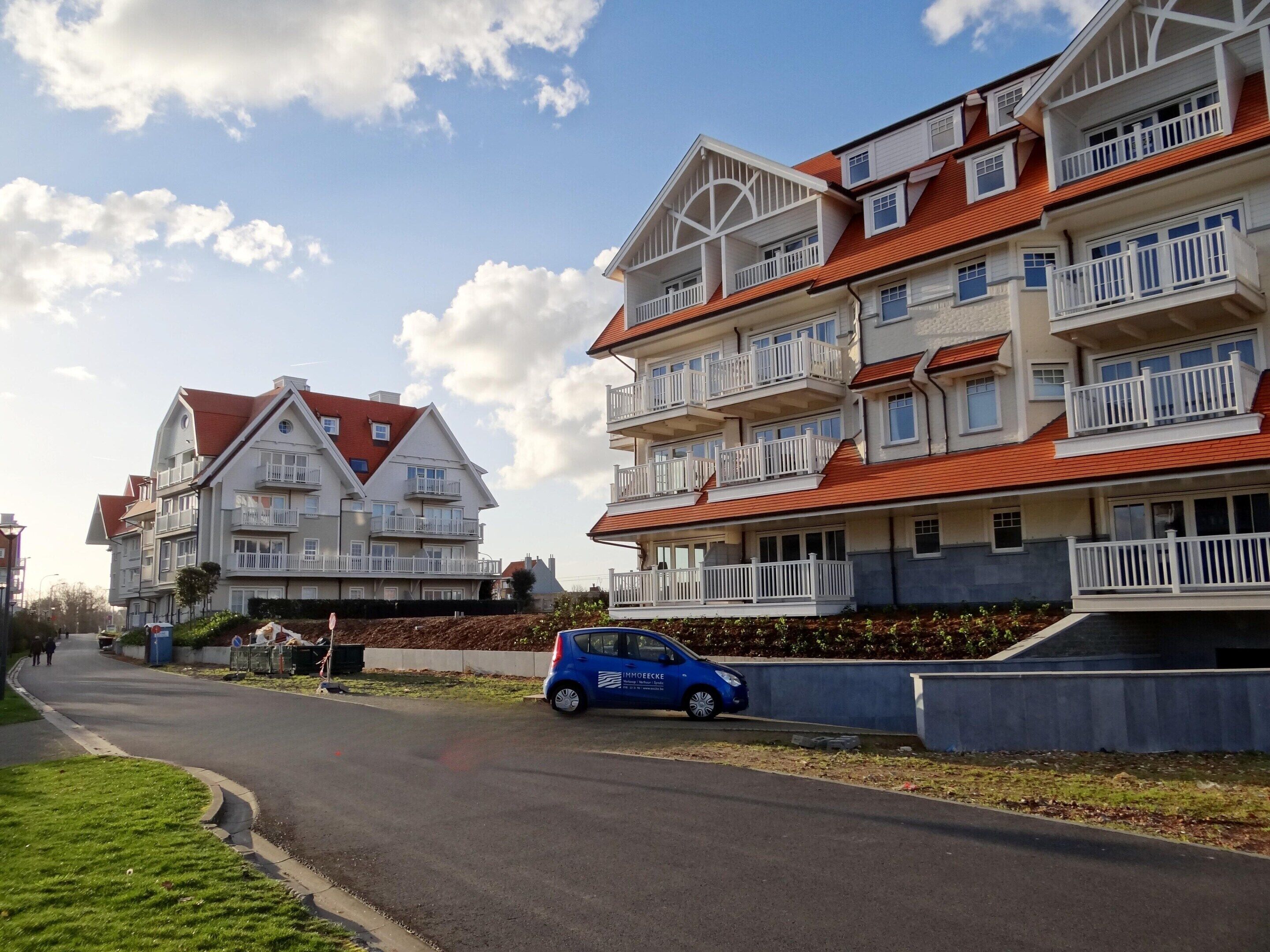 A residential building with multiple balconies and a red roof.