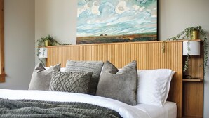 Een slaapkamer met een houten hoofdeinde, een groot landschap en een pluizig vloerkleed.