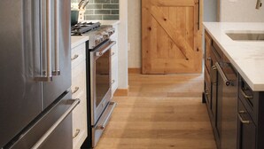 Een moderne keuken met roestvrijstalen apparatuur, houten vloeren en een schuifdeur in boerderijstijl.