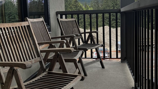 Een balkon met houten stoelen en uitzicht op besneeuwde bergtoppen.