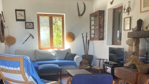 En hyggelig stue med sofa, lænestole, fjernsyn og pejs.