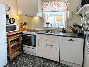 Une cuisine compacte équipée d’un four à micro-ondes, d’une cuisinière, d’un évier et d’étagères en bois.