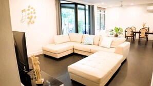 A modern living room with a sectional sofa, a flat-screen TV, and a statue. - Welcome to Tropica Bliss! Just 1.6 KM from Darwin CBD (Stuart Park)