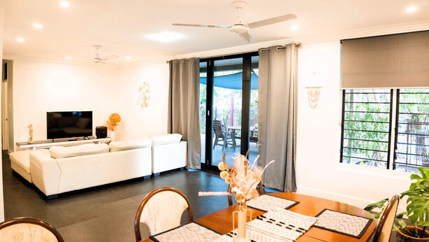 A modern living room with a sofa, TV, and dining area with a table and chairs. - Welcome to Tropica Bliss! Just 1.6 KM from Darwin CBD (Stuart Park)