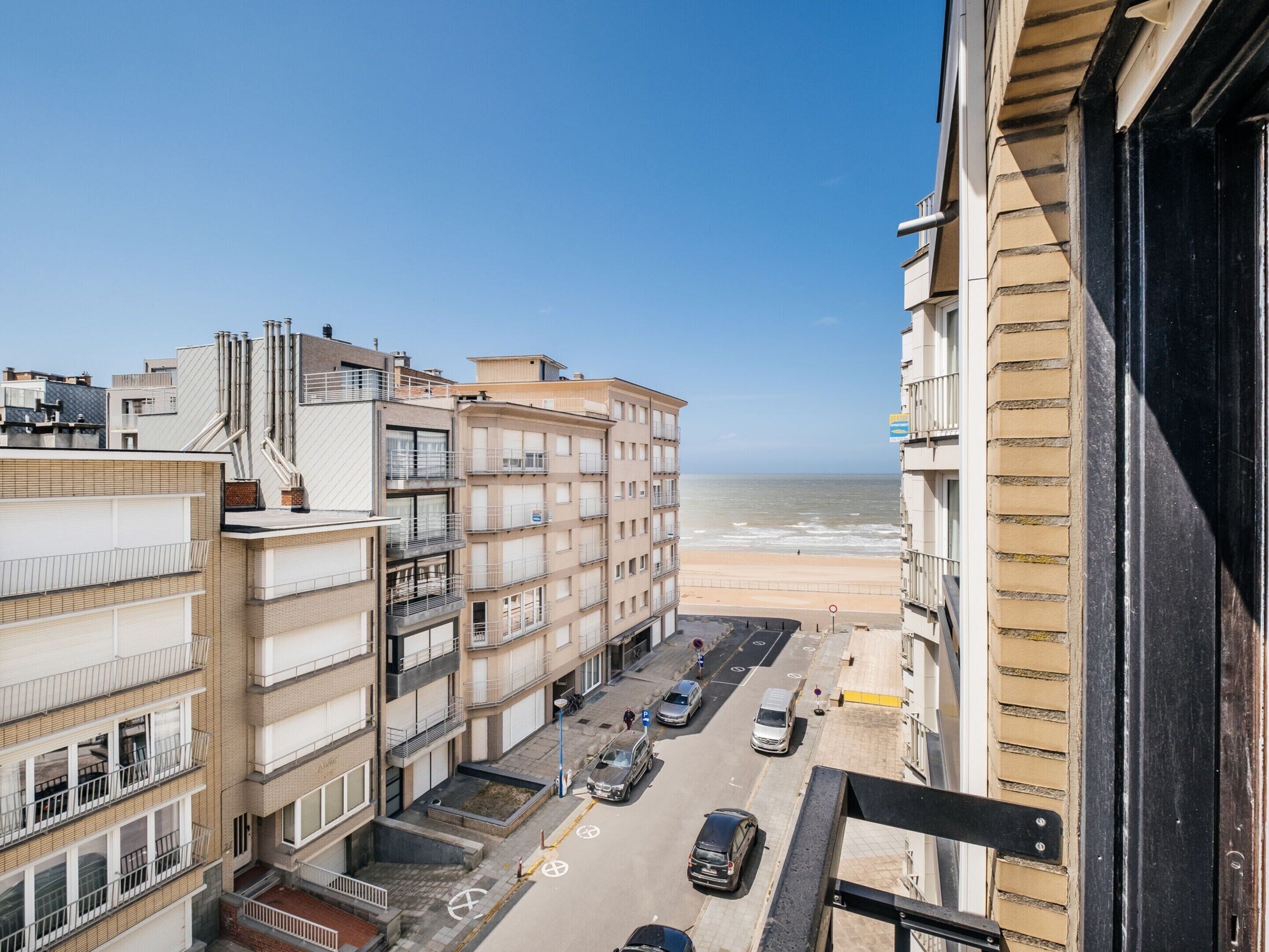 A high-rise building with multiple balconies overlooking a beach.