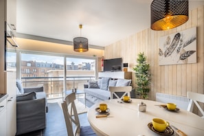 Un salon moderne avec un coin repas, de grandes fenêtres et une vue sur le paysage urbain.