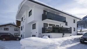 Un bâtiment moderne à deux étages, doté de grandes fenêtres et d’un toit plat recouvert de neige.