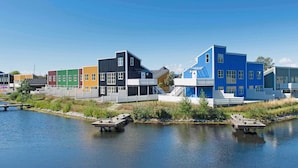 A waterfront property with colorful buildings, a dock, and a calm lake. - Hliday Home on a Holiday Park in Ebeltoft (Ebeltoft)