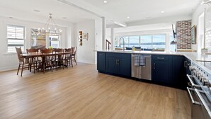 A spacious kitchen with a large island, wooden dining table, and chairs.
