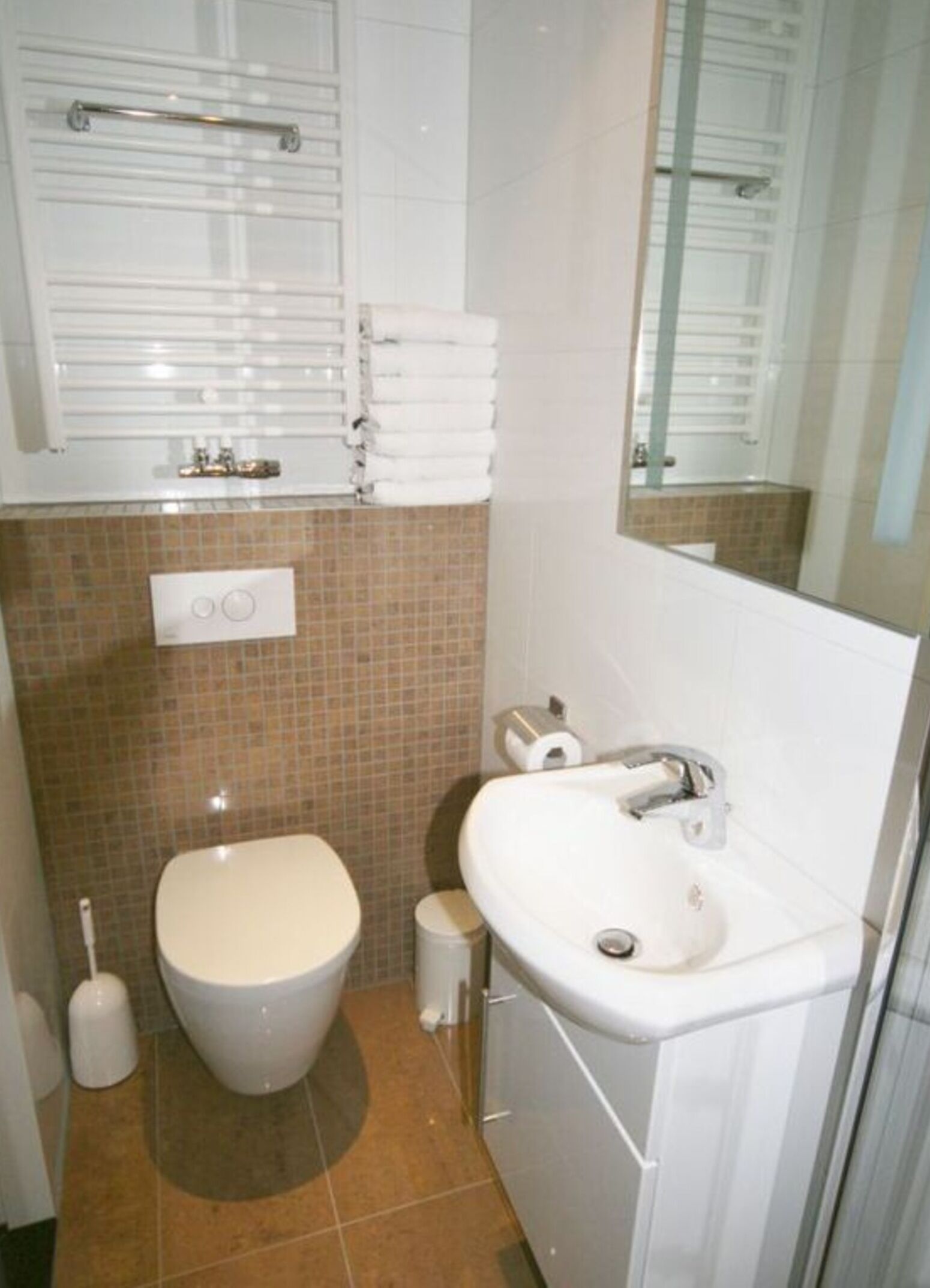 Een badkamer met toilet, wastafel en een handdoekhouder boven de wastafel.