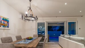 A modern dining area with a wooden table, grey upholstered chairs, and a chandelier.