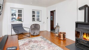 A living room with a fireplace, a sofa, a coffee table, and a rug. - 6 Person Holiday Home in Logstor (Logstor)