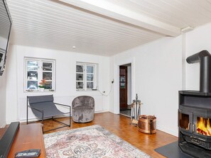 A living room with a fireplace, a sofa, a coffee table, and a rug. - 6 Person Holiday Home in Logstor (Logstor)