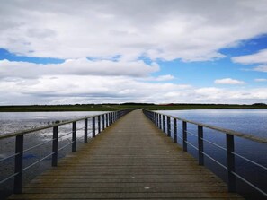 A wooden pier extending into a body of water, with a metal railing on both sides and a cloudy sky above. - 6 Person Holiday Home in Logstor (Logstor)