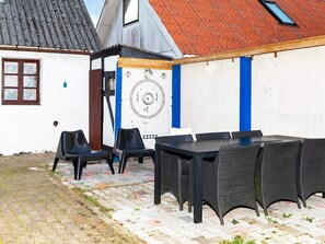 A courtyard with a table and chairs, a decorative wall, and a building with a red roof. - 6 Person Holiday Home in Logstor (Logstor)