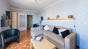 Ein modernes Wohnzimmer mit einer Couch, einem Couchtisch, einem schwarzen Sessel und einem Holzboden mit Dekorationselementen.