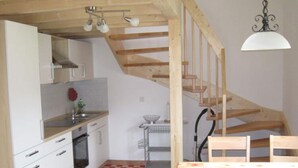 Una cocina con armarios blancos, una escalera de madera y una mesa de comedor con sillas.