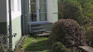 Un bâtiment à deux étages, doté d’un coin arrondi, d’un petit porche à l’avant et d’une fenêtre avec un rideau.