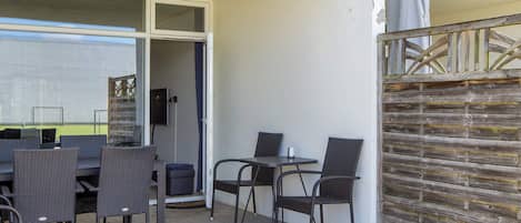 An outdoor patio with a table and chairs, a covered area, and a wooden fence.