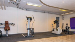 Un gimnasio con máquinas de cardio, una bicicleta estática y una máquina de remo.