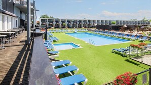 Un área de piscina con múltiples sillas de descanso y una piscina pequeña.