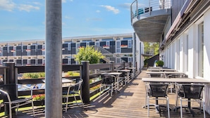 A wooden deck with outdoor seating and a view of a building with balconies. - 4 Person Holiday Park Home in Glesborg (Glesborg)
