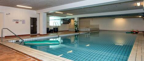 An indoor swimming pool with tiled walls and a wooden floor.