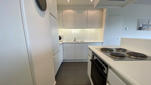 A modern kitchen with white cabinets, a built-in oven, and a stovetop. - Apartment in Nieuwpoort With Terrace (Nieuwpoort)